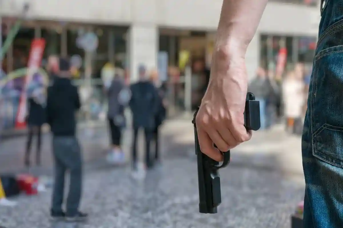 Преступник держиит пистолет на улице