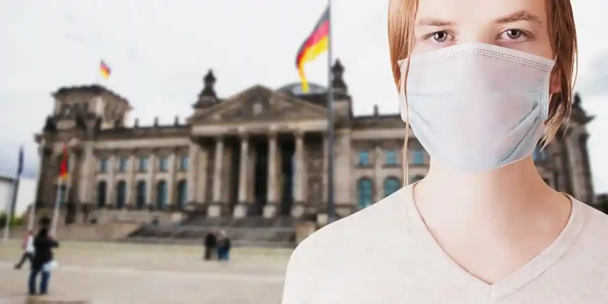 Женщина в маске на фоне Бундестага в Берлине
