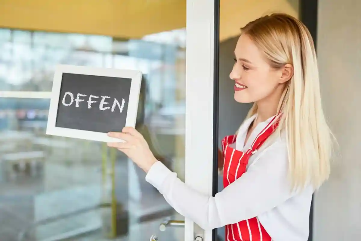 Официантка вещает на двери немецкого кафе табличку Offen фото