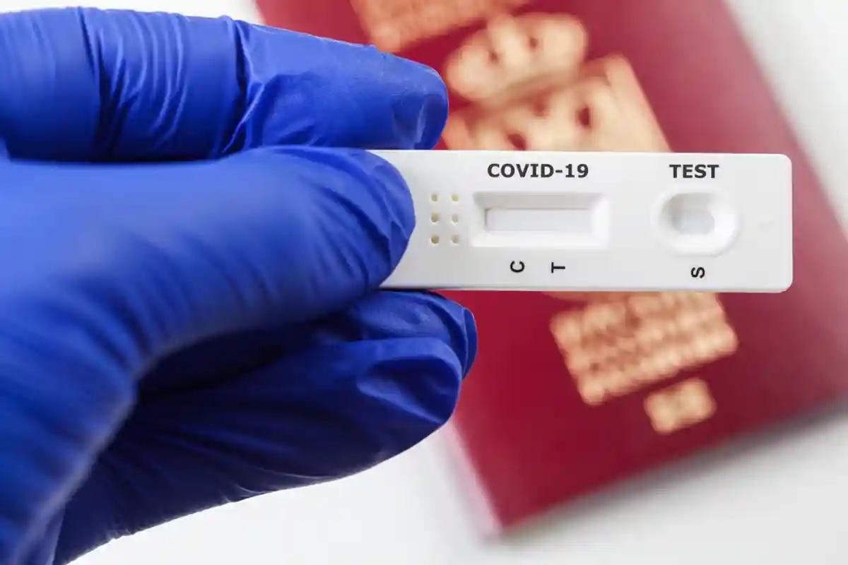 экспресс-тест на коронавирус в руке на фоне паспорта