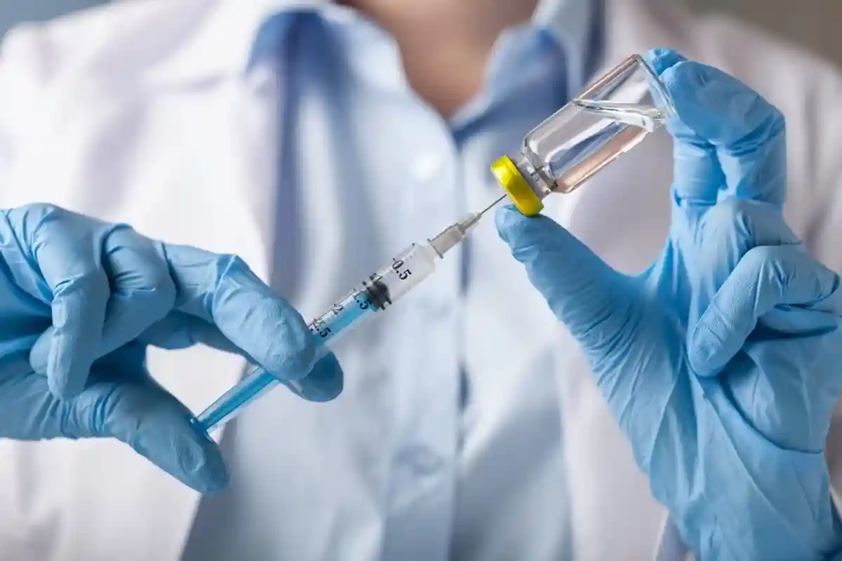 врач набирает вакцину шприцом фото