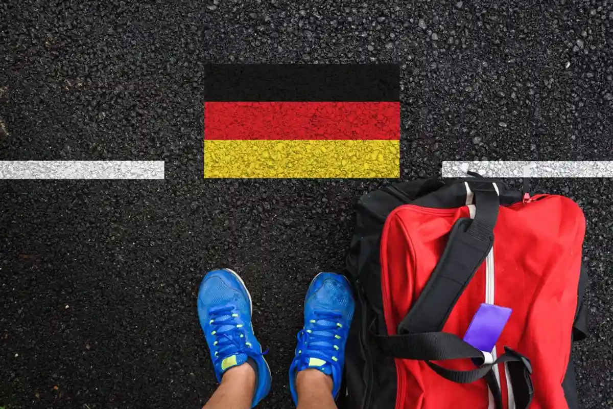 Мужчина с чемоданом у немецкого флага на асфальте фото