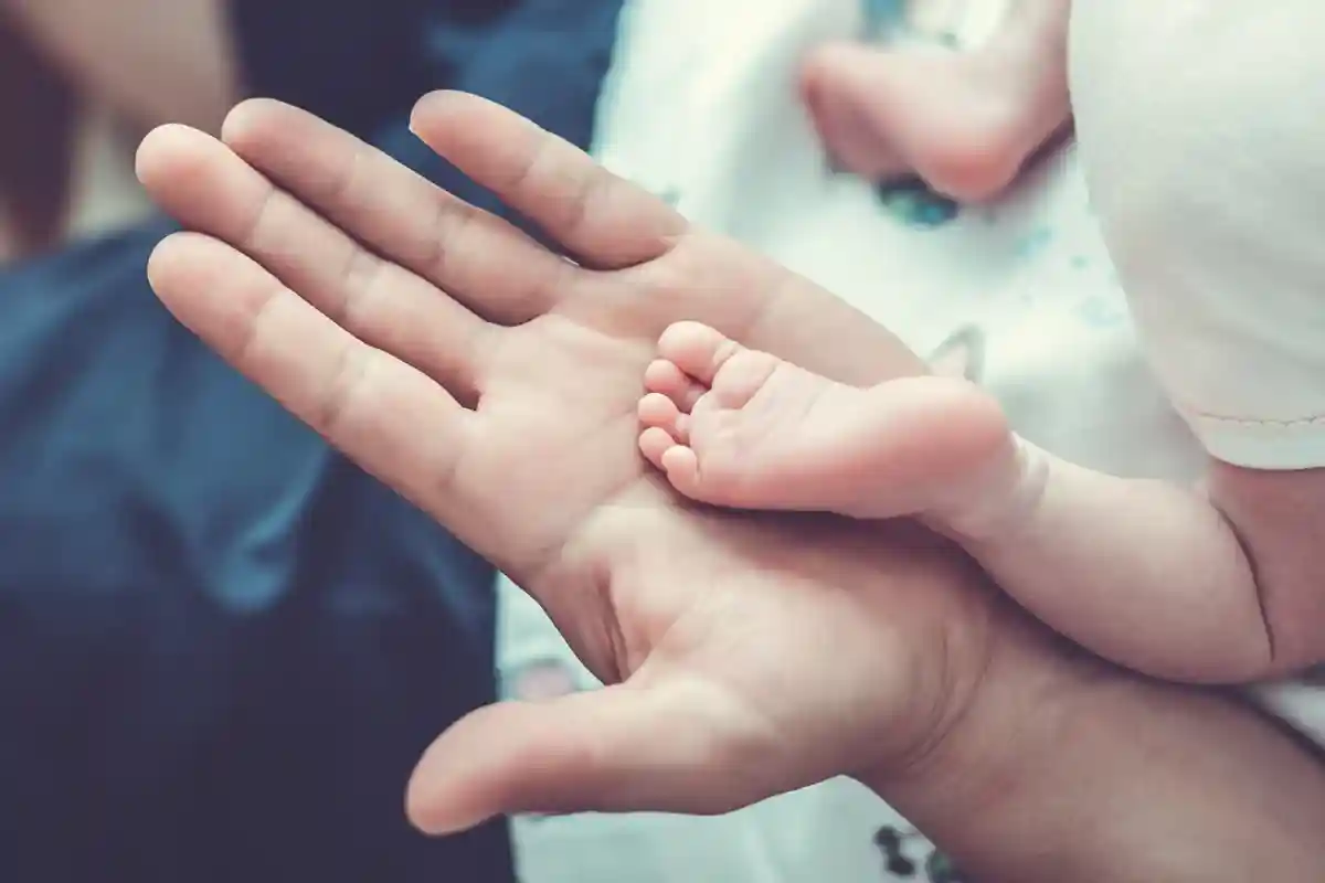 Ножка младенца в руках у папы фото