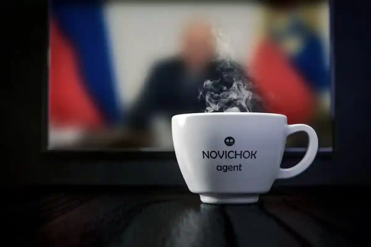 Белая чашка с надписью "Новичёк" на фоне русских новостей фото