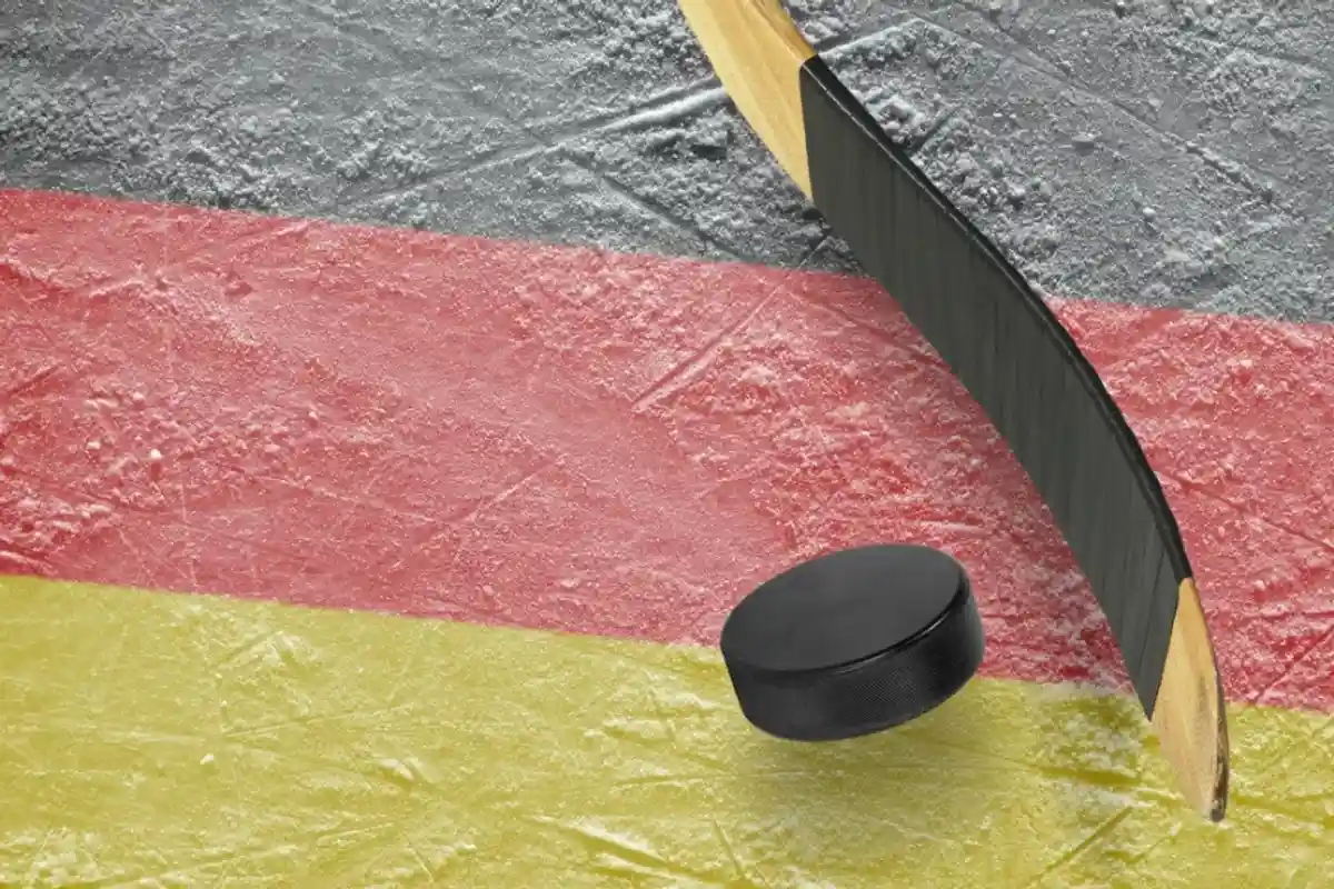 Хоккейная клюшка и шайба на фоне цветов немецкого флага фото