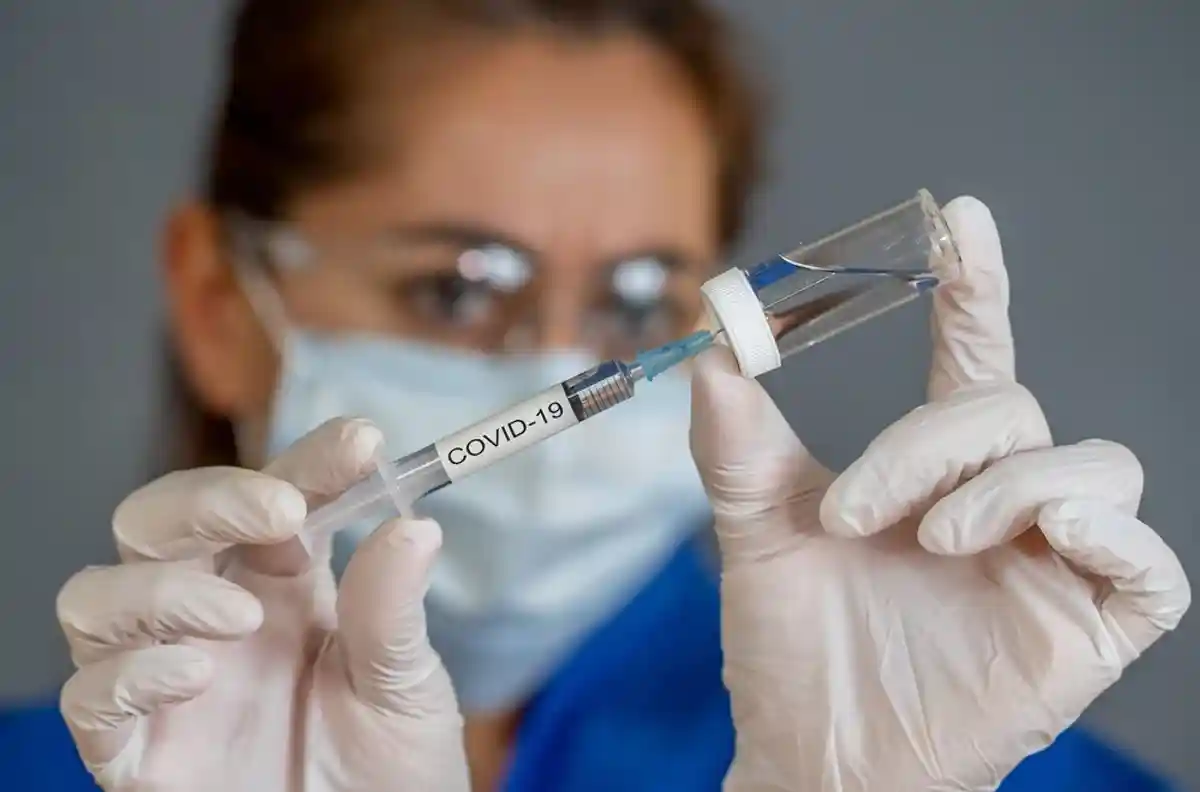 медсестра набирает вакцину в шприц фото
