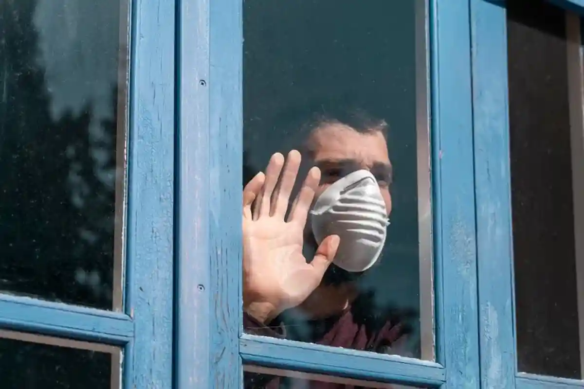 мужчина на карантине смотрит в окно фото