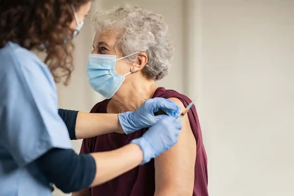врач вводит вакцину пожилой женщине фото