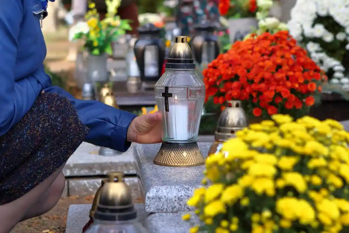 Женщины на кладбище ставят свечу на могилу Фото: wideonet/Shutterstock.com