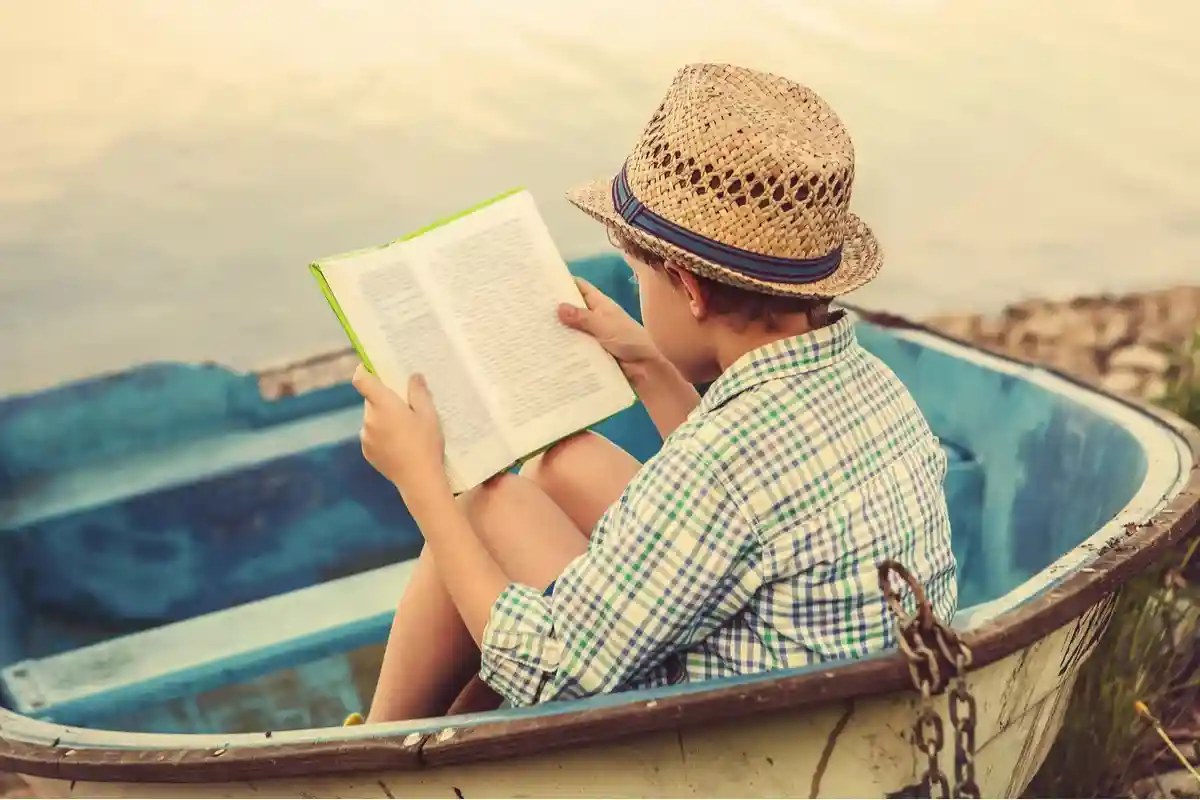 Читающий мальчик в старой лодке Фото: Soloviova Liudmyla/Shutterstock.com