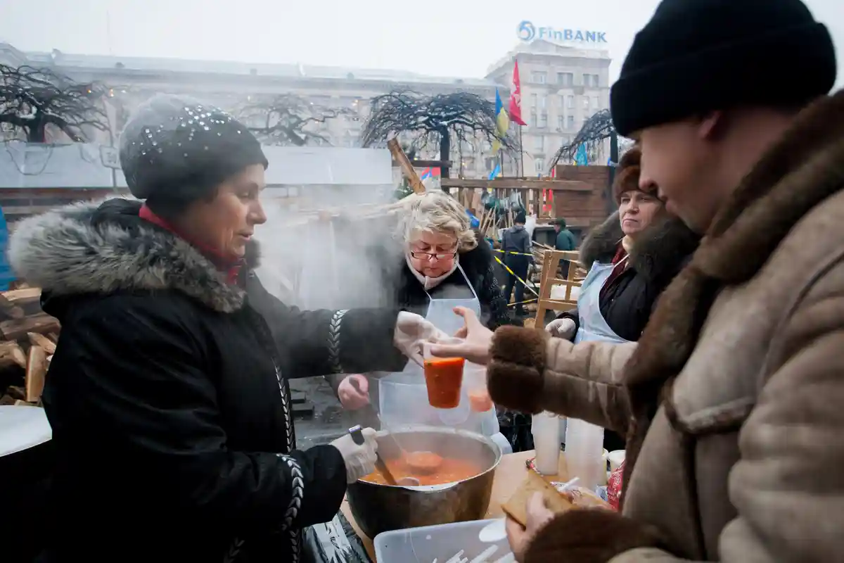 Женщина раздает жителям горячую еду. Фото: Radiokafka / Shutterstock.com.
