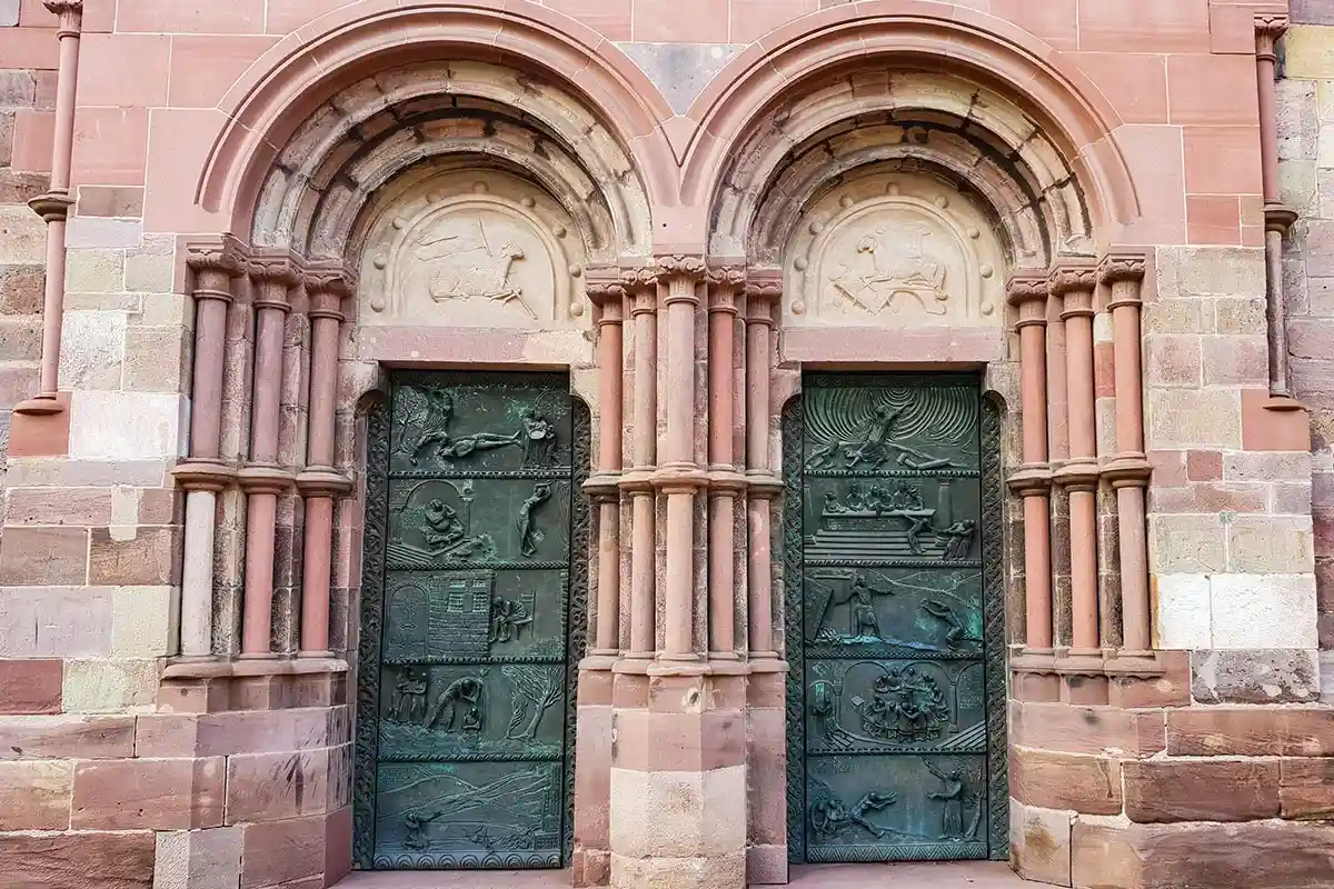 расивый орнамент на дверях средневекового немецкого собора, контраст серой стали входа и массивных красных камней. Фото: shutterstock.com