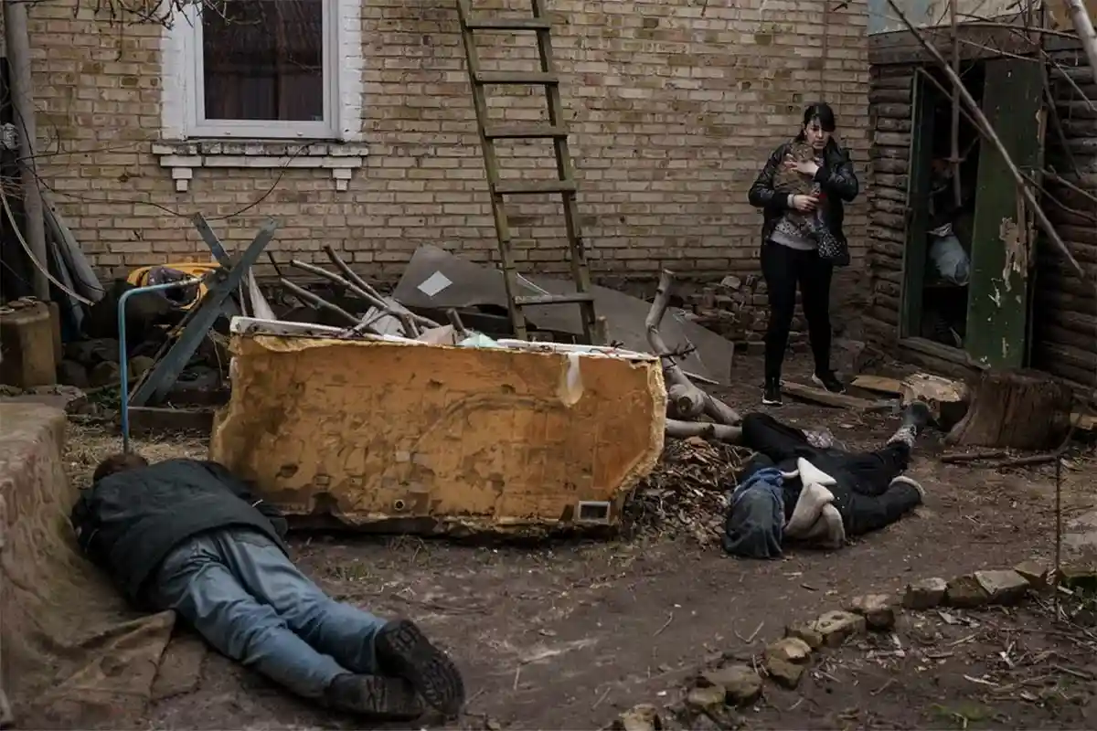 Жительница Бучи и тела ее погибших мужа и брата, убитых во дворе их дома. Фото: Felipe Dana
