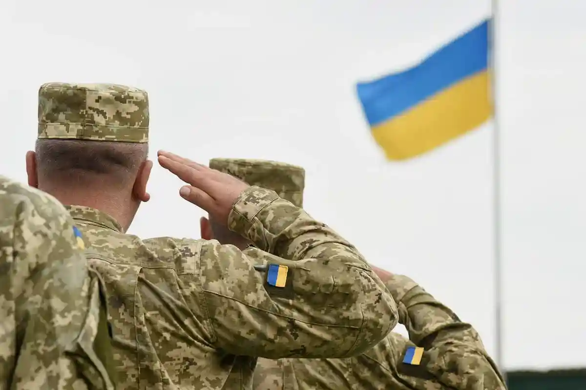 Украинские воины салютуют государственному флагу Украины. Фото: shutterstock.com
