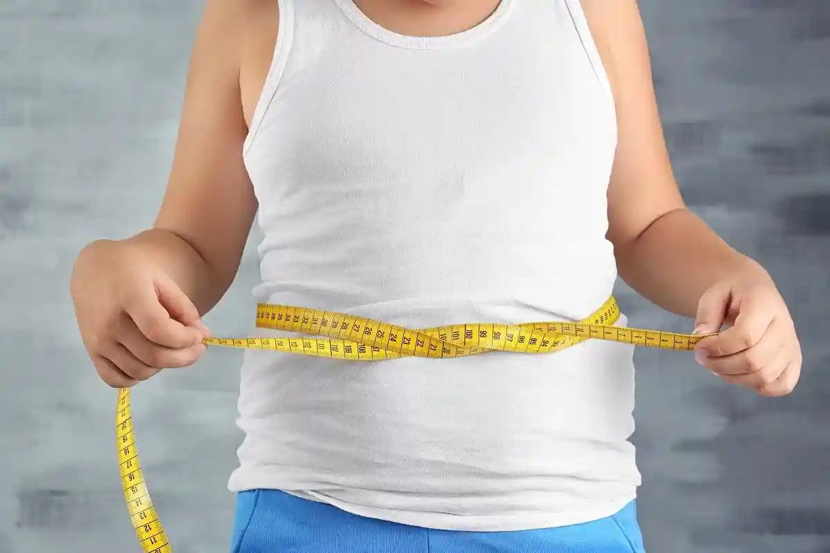 Толстый мальчик измеряет талию