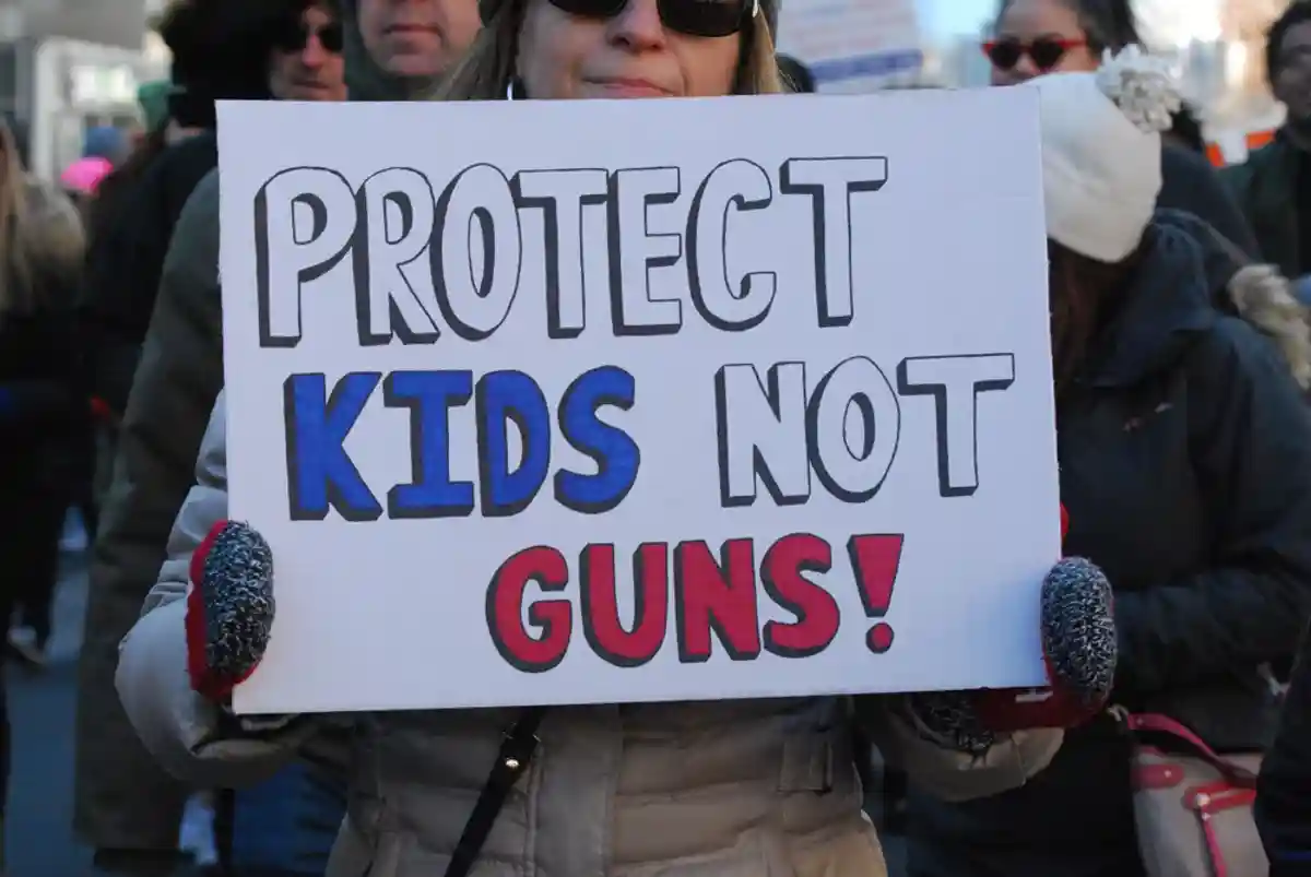 Участница демонстрации с плакатаом, на котором написано «Защитите детей, а не оружие». Фото: LouiesWorld1 / Shutterstock.com