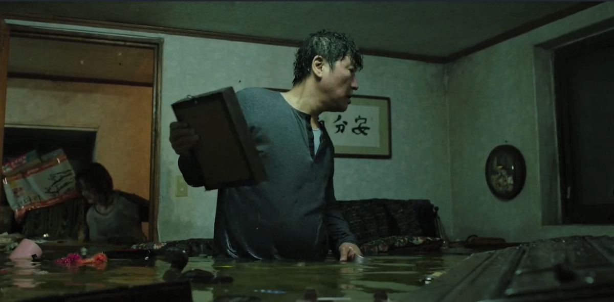 Наводнение в Сеуле напомнило сцену из оскароносного фильмы «Паразиты», где главные герои спасают вещи из затопленной полуподвальной квартиры. Фото: кадр из фильма «Паразиты».