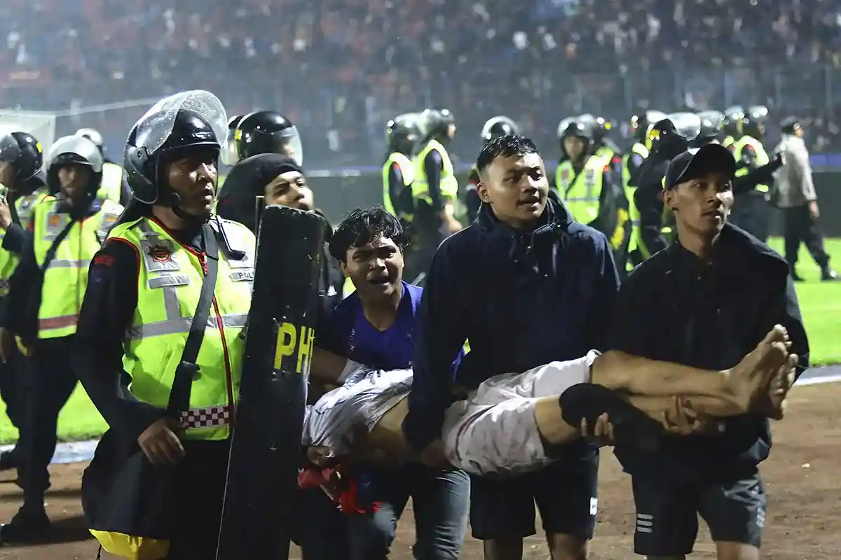Трагедия на футбольном поле в Индонезии. Футбольные фанаты несут раненого мужчину со стадиона. Фото: Yudha Prabowo