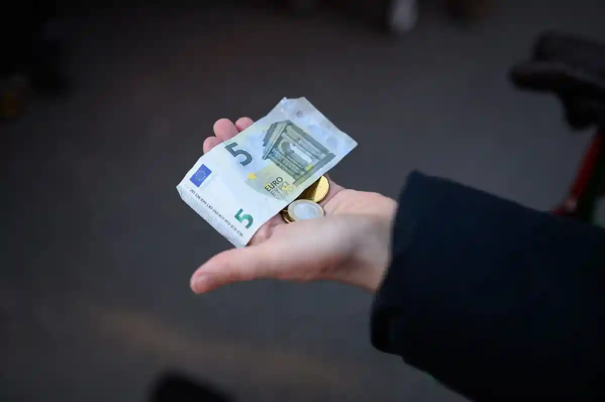 Деньги:Женщина держит в руке деньги за покупку.