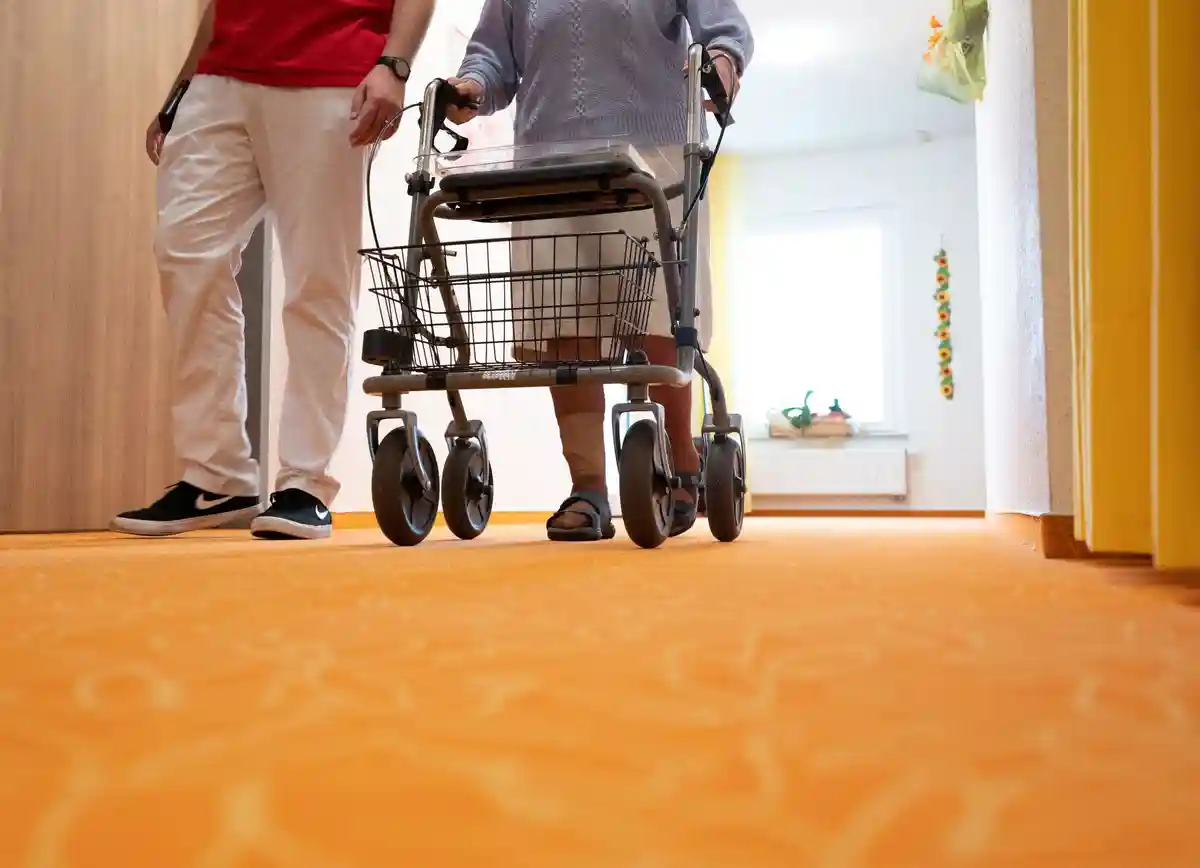 Дом престарелых:Сиделка идет по коридору вместе с пациентом дома престарелых.