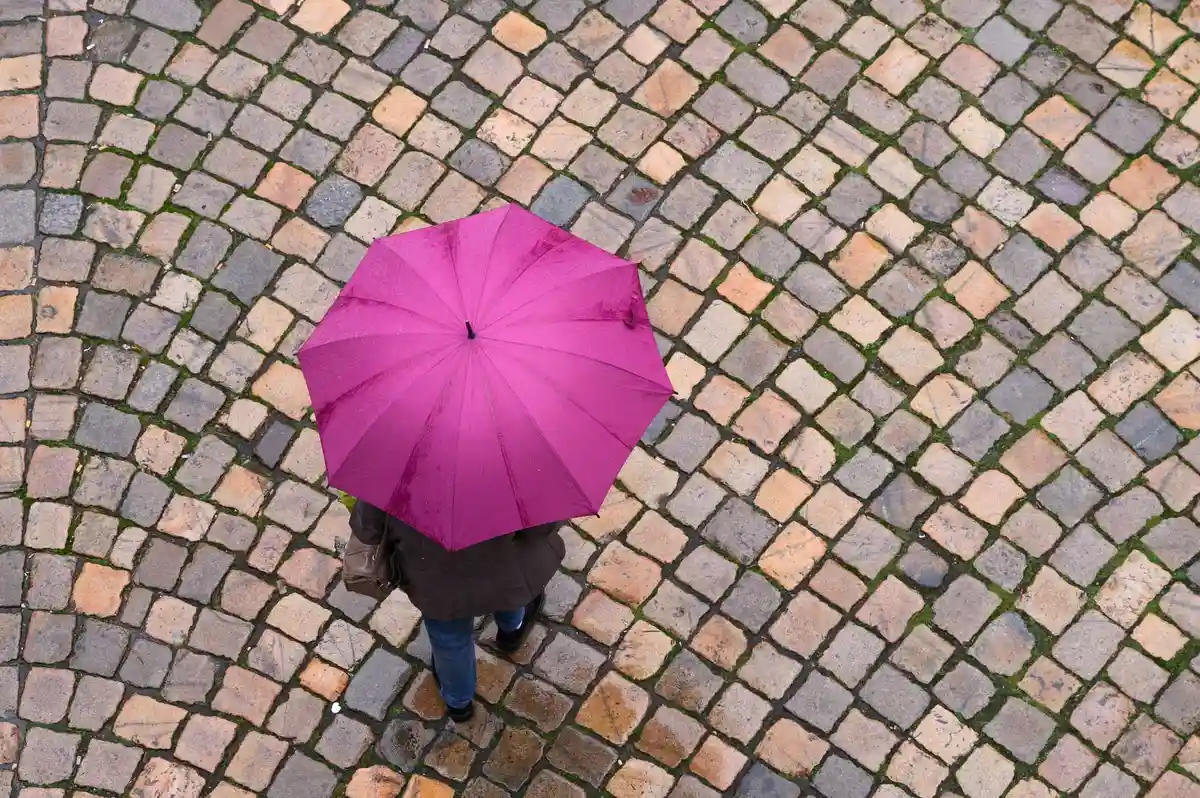 Дождливая погода:Женщина идет по улице с зонтиком.