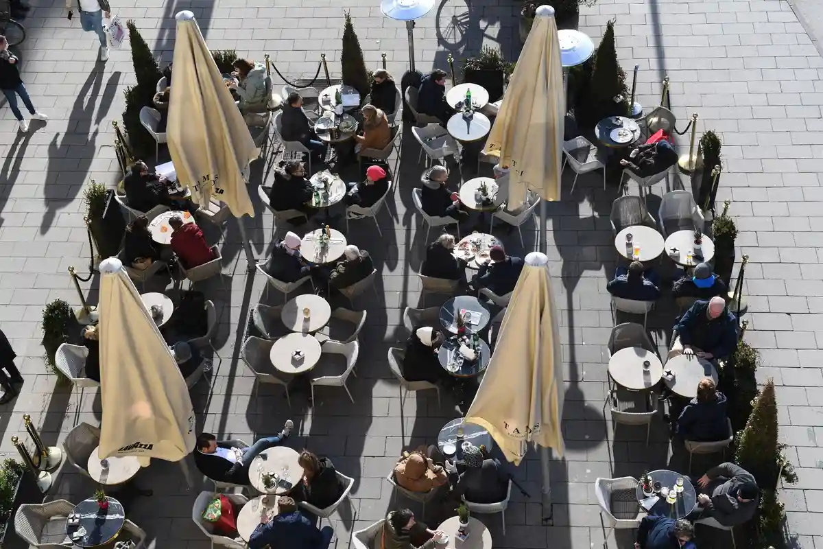 Гастрономия:Гости сидят на солнце перед кафе.