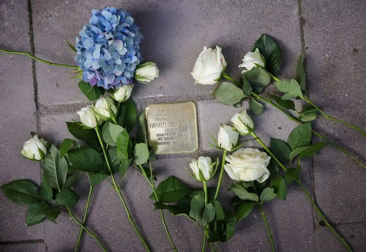 Камень преткновения для ночного портье Харальда Селигманна:Розы и другие цветы лежат рядом со свежеуложенным камнем преткновения перед отелем Vier Jahreszeiten.