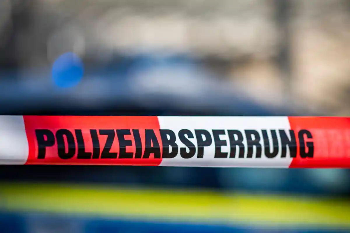 Полицейское оцепление:Перед полицейской машиной натянута заградительная лента с надписью "Polizeiabsperrung".