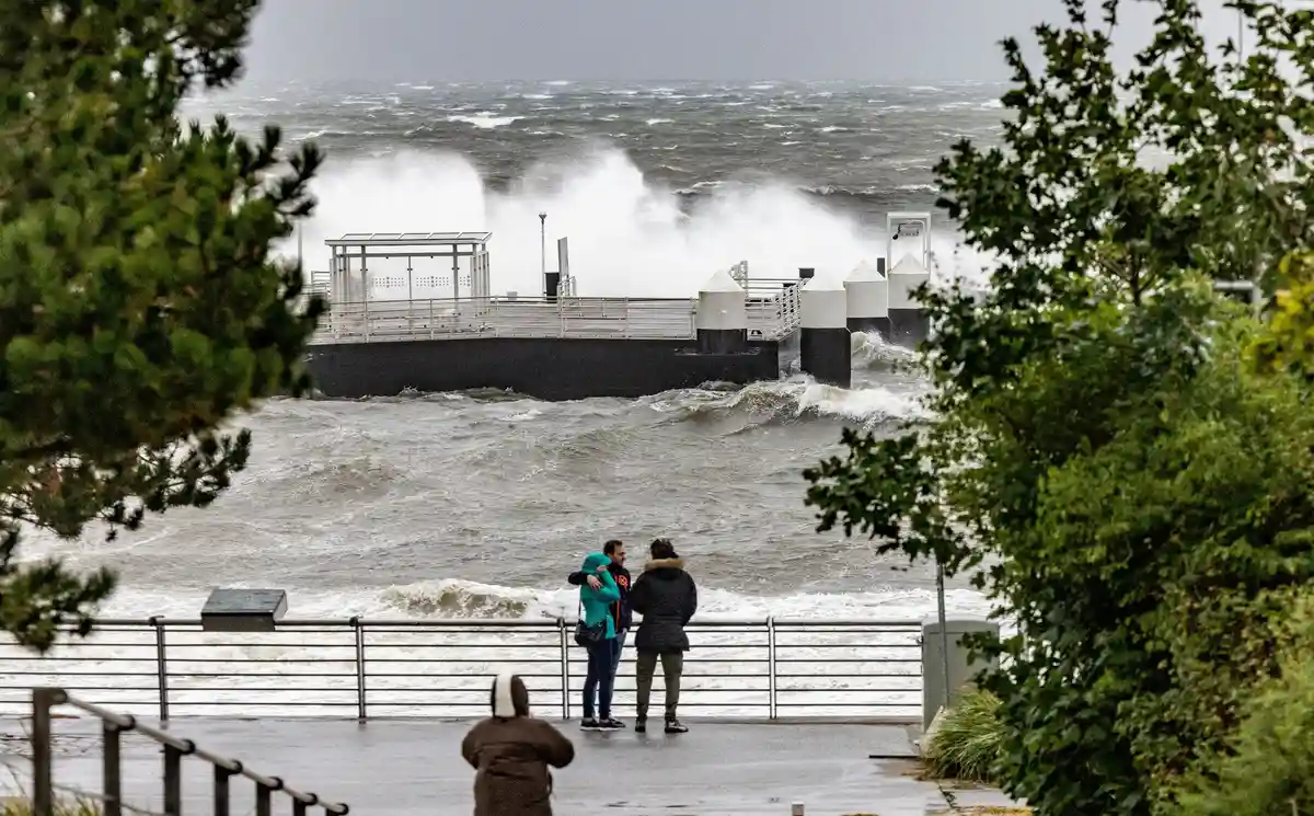 Штормовой нагон на Балтийском побережье:Посетители гавани в Шильксее фотографируют волны, разбивающиеся о портовые сооружения.