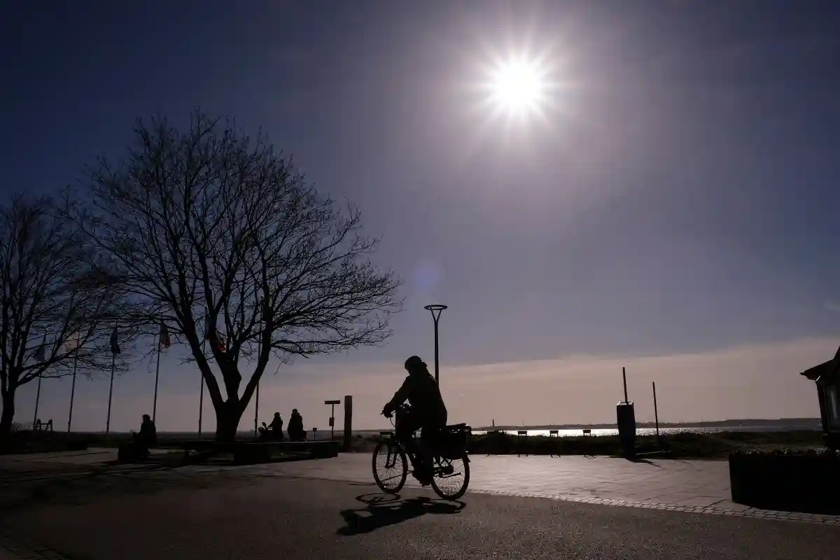 СПД за более дружелюбные к велосипедистам министерства:Женщина едет на велосипеде вдоль Балтийского моря в контровом свете.