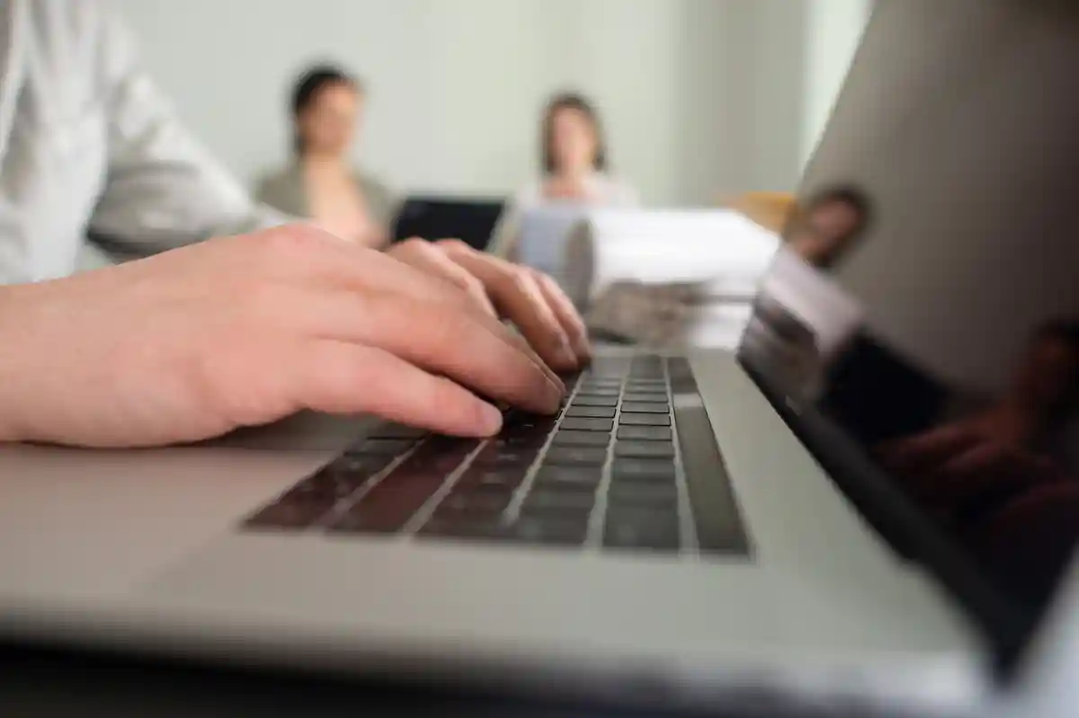 Трудовая жизнь в Германии:Мужчина набирает текст на клавиатуре ноутбука в офисе.