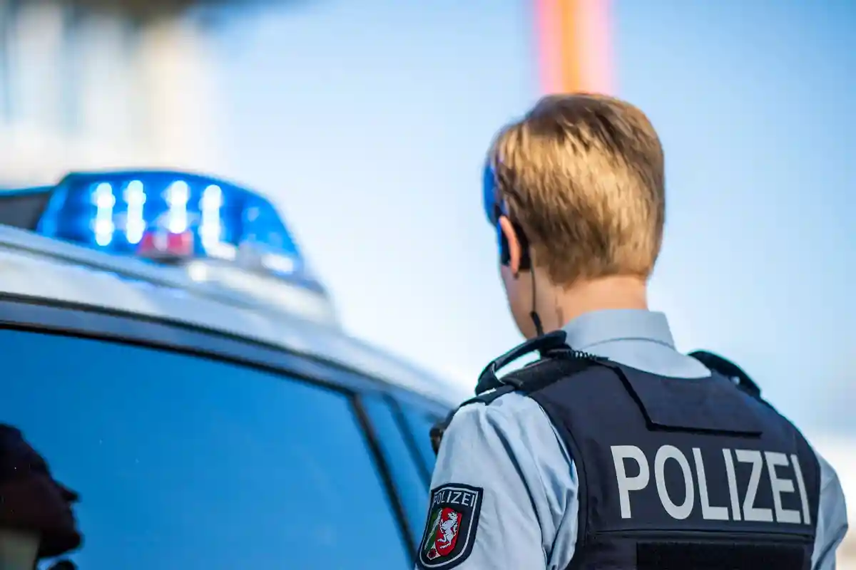 Женщина-полицейский в Северном Рейне-Вестфалии:Женщина-полицейский стоит перед патрульной машиной.