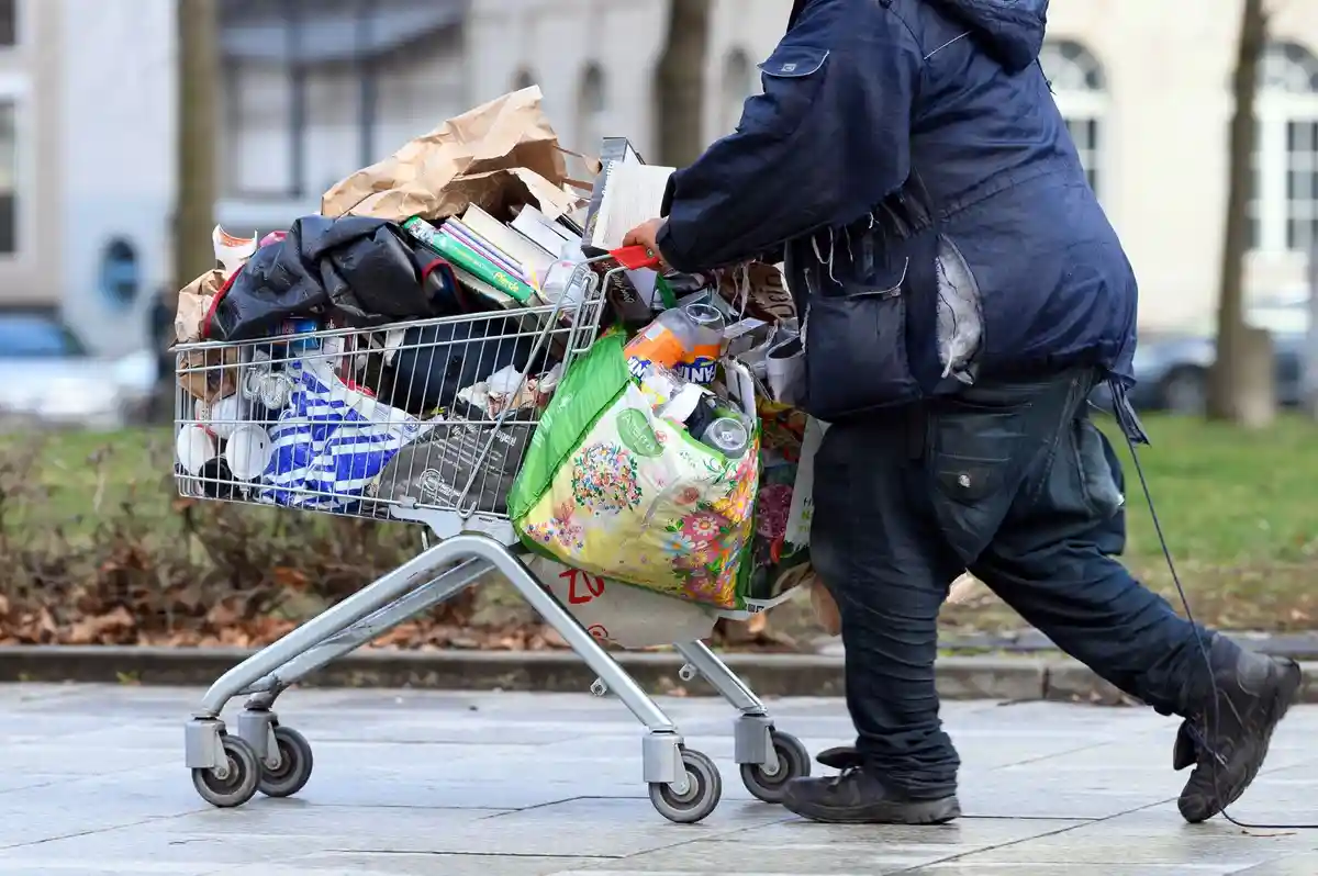 Бедность:Бездомный толкает тележку с покупками по пешеходной улице в Берлине.