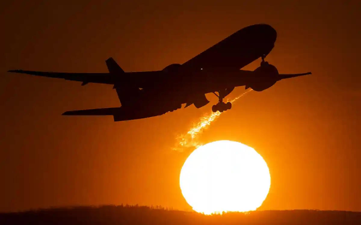 Аэроплан:Пассажирский самолет взлетает из аэропорта Франкфурта на фоне заходящего солнца.