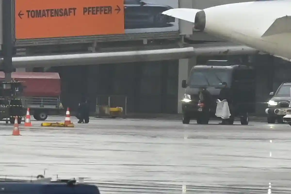 Аэропорт Гамбурга:Захватчик заложников (л) стоит на коленях на полу со своим ребенком - сотрудник полиции приносит одеяло.