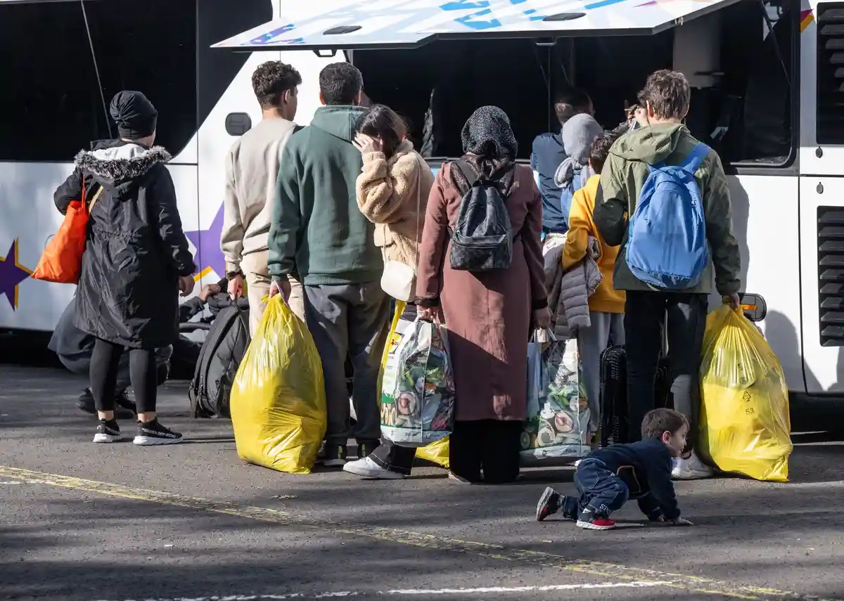 Беженцы в центре первичного приема:Беженцы идут к ожидающему их автобусу в центре первичного приема беженцев (HEAE).
