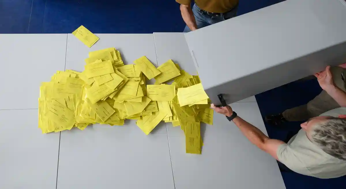 Бюллетень для голосования:Конверты с бюллетенями для почтового голосования высыпаются из урны для голосования.