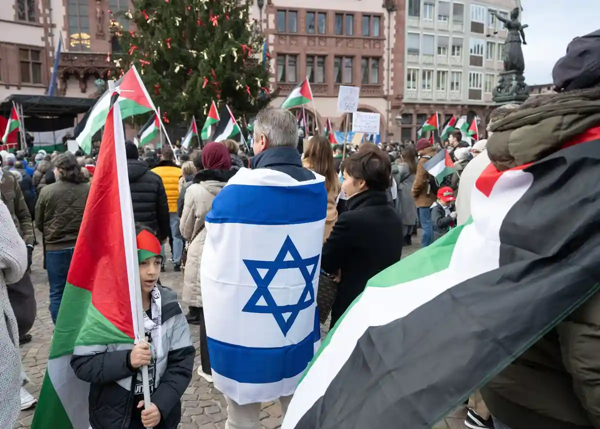 Ближневосточный конфликт - Демонстрация во Франкфурте-на-Майне:Мужчина с израильским флагом стоит среди демонстрантов, выступающих за Палестину, на митинге.