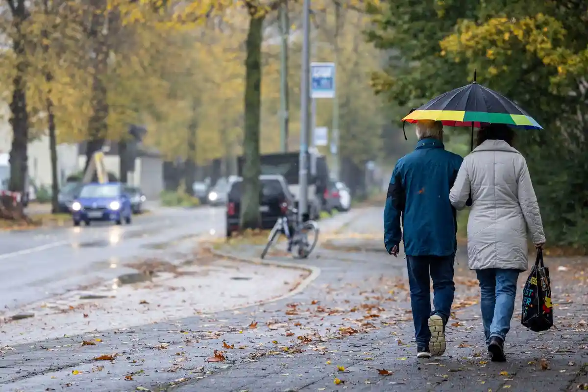 Дождь в Дуйсбурге - Погода в земле Северный Рейн-Вестфалия:Прохожие с зонтиками идут по тротуару под дождем.
