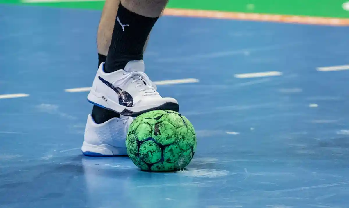 Гандбол:Игрок удерживает гандбольный мяч ногой.