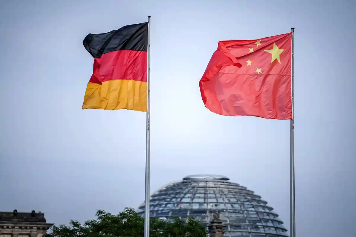 Германия Китай Флаги:Флаги Германии и Китая развеваются перед зданием Федеральной канцелярии в начале визита представителей китайского правительства в Германию, на заднем плане - купол здания Рейхстага.