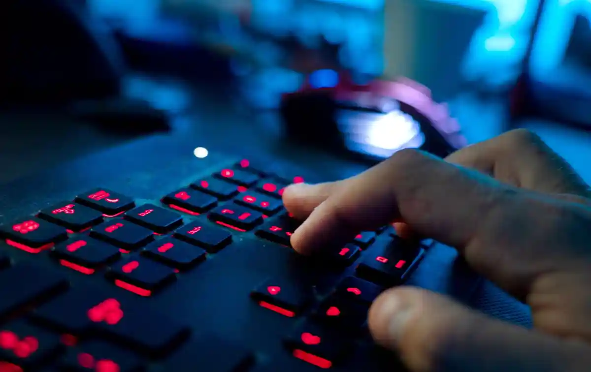 Кибербезопасность:Мужчина сидит за компьютером и набирает текст на клавиатуре.