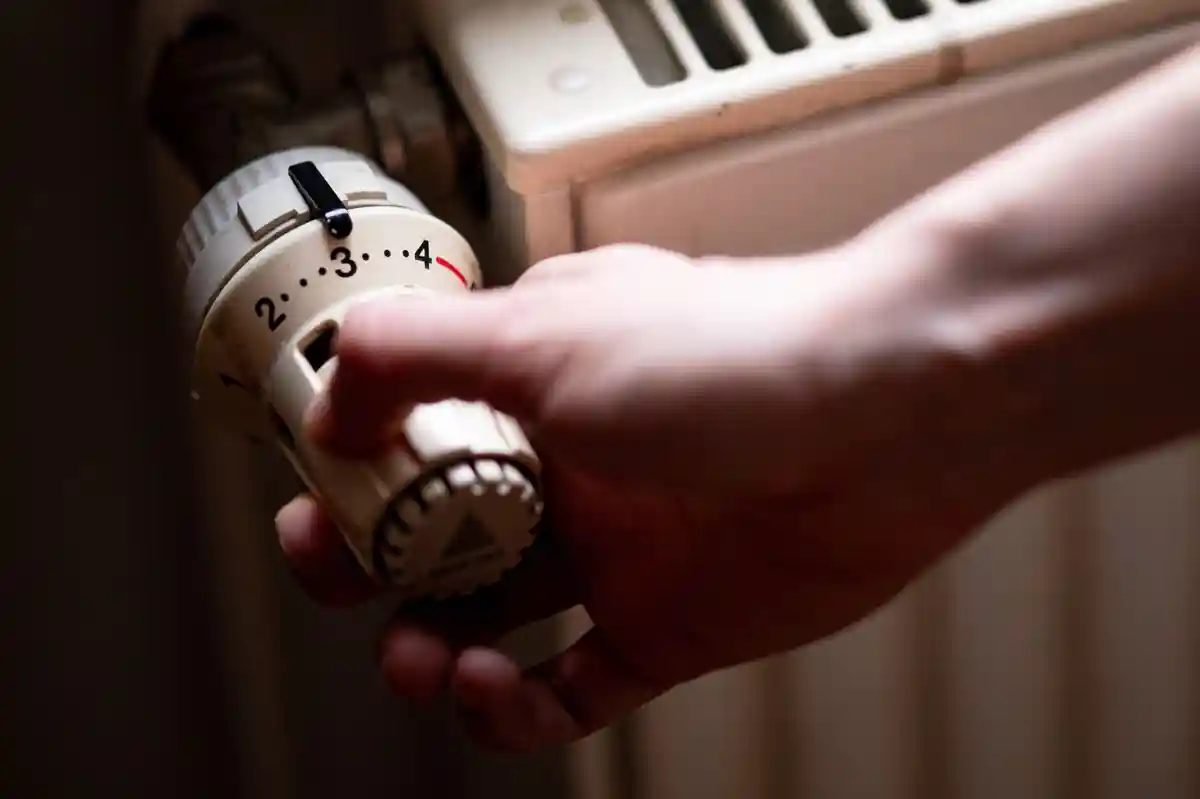 Отопление и нагревательный термостат:Человек пользуется старым радиатором в старой квартире в Берлине.