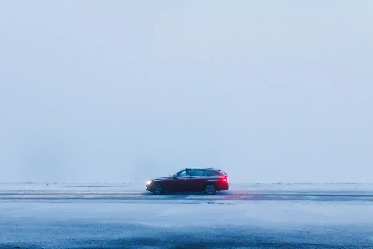 Путешествие на автомобиле зимой:Автомобиль едет по заснеженной дороге в густом тумане.
