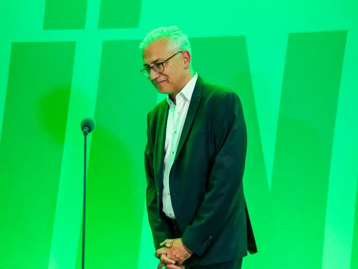 Тарек Аль-Вазир:Тарек Аль-Вазир (Bündnis 90 / Die Grünen), заместитель премьер-министра и министр экономики земли Гессен, стоит перед своими коллегами по партии, залитый зеленым светом.