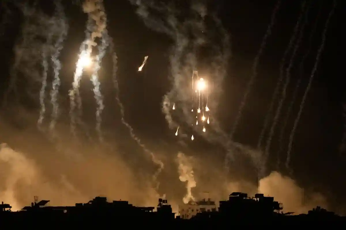 Война:Дым поднимается вверх, и осветительные ракеты освещают небо во время израильского авиаудара в секторе Газа.