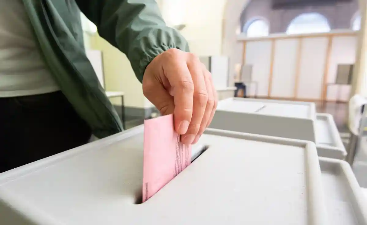 Выборы:Мужчина бросает свой бюллетень в урну.