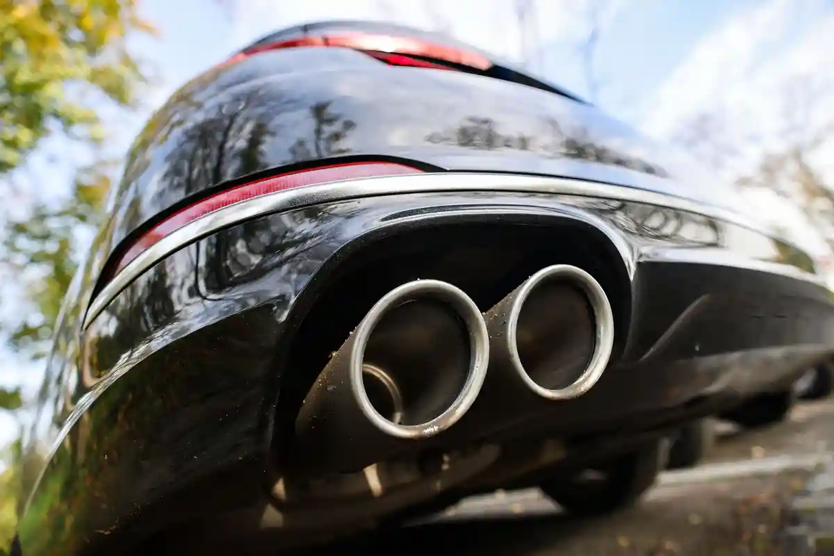 Выхлопные газы:Автомобиль с двойной выхлопной трубой припаркован на стоянке.