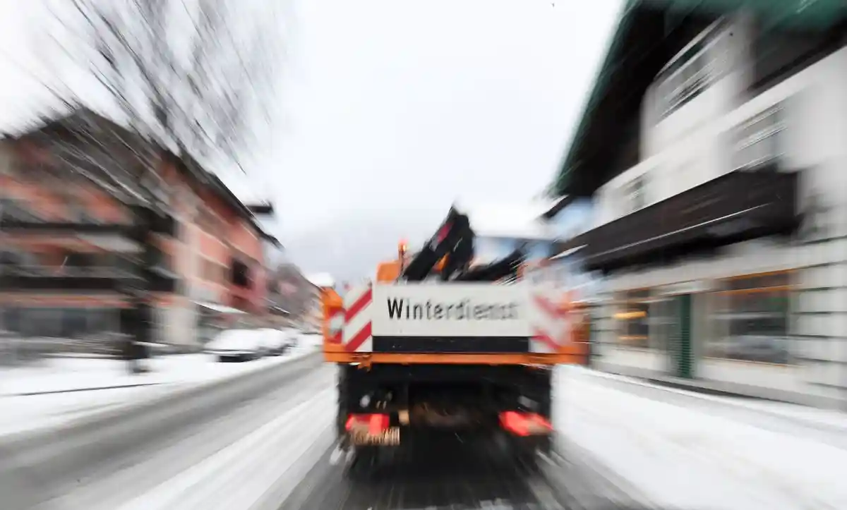 Зимний сервис:Машина для обслуживания зимних дорог проезжает по дороге.