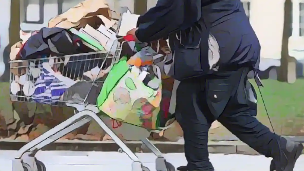 Бездомный толкает тележку с покупками по пешеходной улице в Берлине.:Бездомный толкает тележку с покупками по пешеходной улице в Берлине. Фото